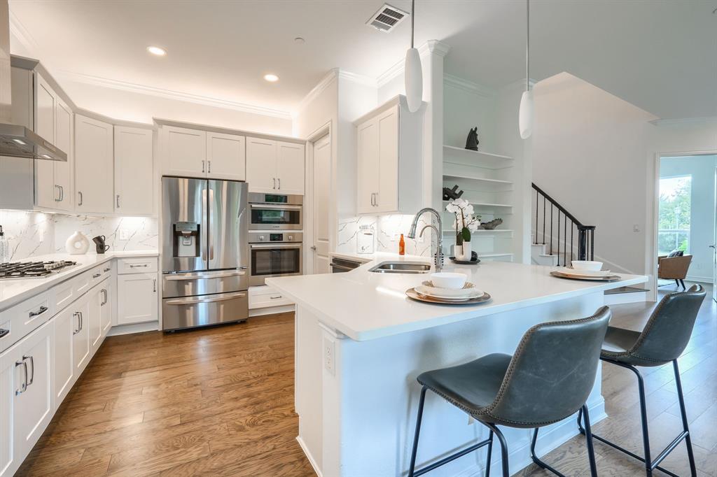 3101 Raphael Court McKinney, TX 75070 - Photo 11 of 40 a kitchen with stainless steel appliances kitchen island granite countertop a kitchen island and chairs in it