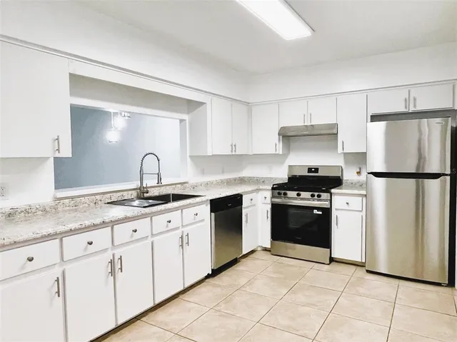 a kitchen with granite countertop a sink stove and refrigerator