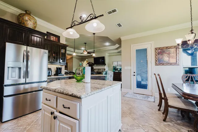 a kitchen with granite countertop a table chairs microwave and refrigerator