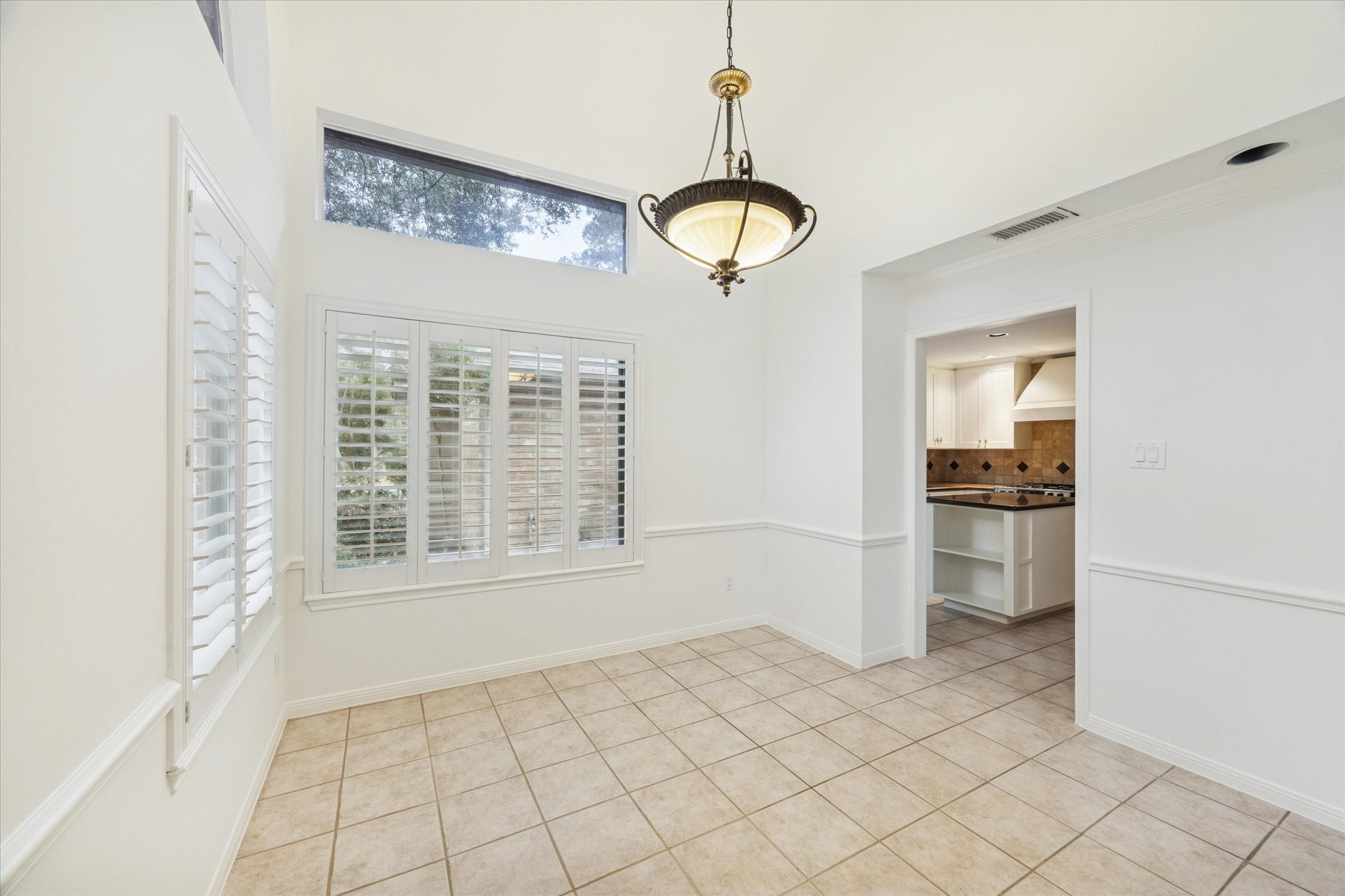 12 Lakeridge Drive Spring, TX 77381 - Photo 6 of 24 Open layout dining area seamlessly connected to the kitchen, featuring tall ceilings, plantation shutters, and designer lighting for an elegant flow.