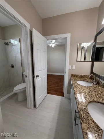 an empty room with wooden floor chandelier fan and windows