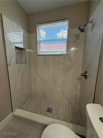 an empty room with wooden floor ceiling fan and windows