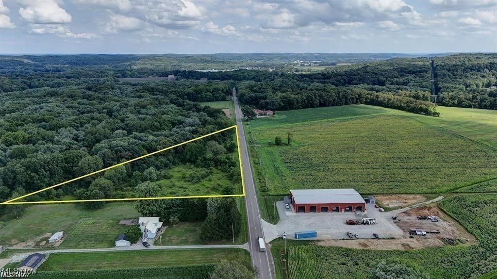 Aerial view of sparsely populated area with property parcel outlined and a forest