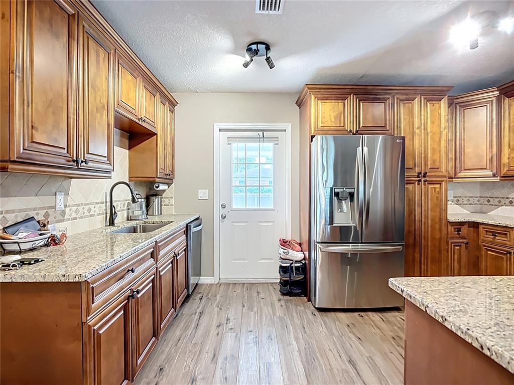 1304 Alfred Street, Unit A Brandon, FL 33510 - Photo 12 of 25 a kitchen with stainless steel appliances granite countertop a refrigerator a sink dishwasher and wooden cabinets with wooden floor
