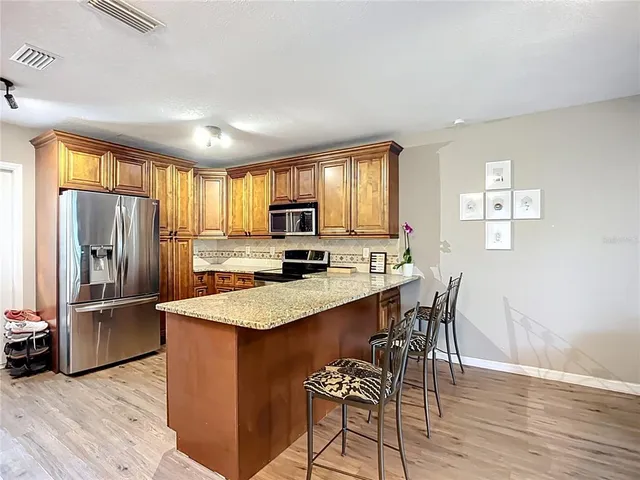 a kitchen with stainless steel appliances granite countertop a refrigerator a stove a sink a dining table and chairs