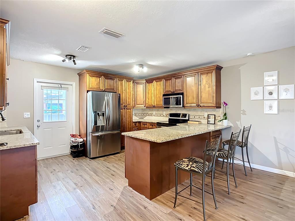 1304 Alfred Street, Unit A Brandon, FL 33510 - Photo 14 of 25 a kitchen with refrigerator a sink dishwasher a dining table and chairs with wooden floor