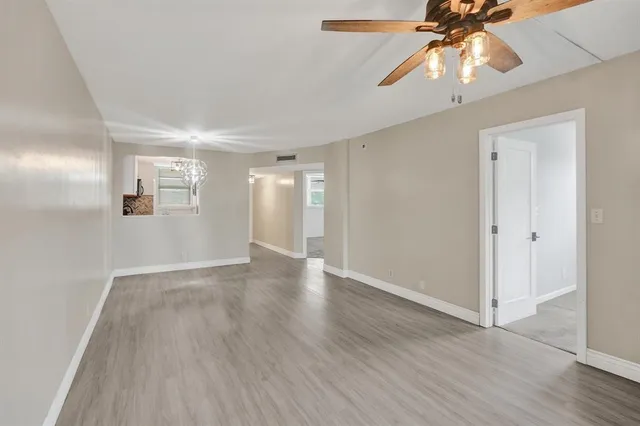 a view of an empty room with window and wooden floor