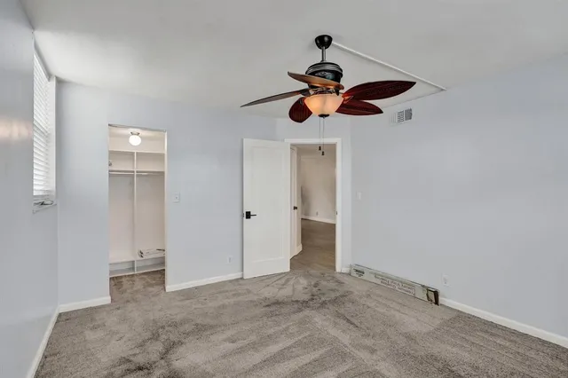 a view of a room with a ceiling fan and carpet