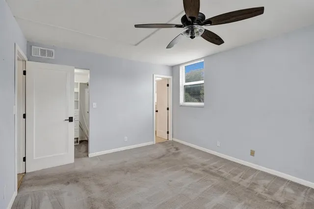 an empty room with windows and fan