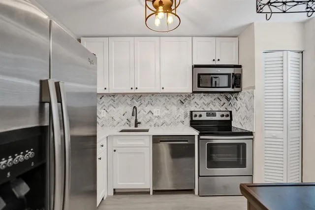 a kitchen with white cabinets and stainless steel appliances