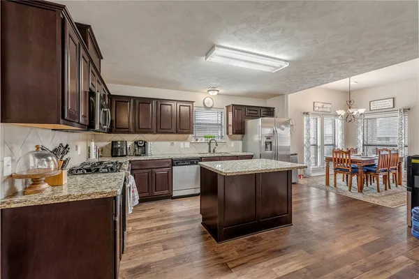 a large kitchen with stainless steel appliances granite countertop a lot of counter space and wooden floors
