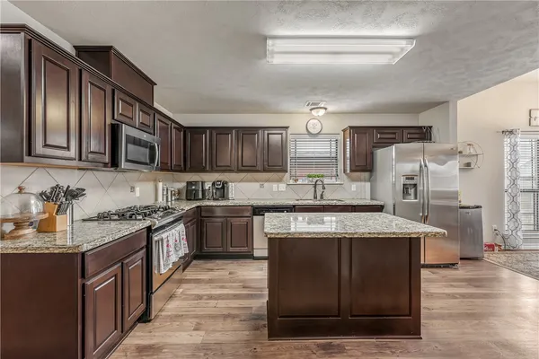 a large kitchen with stainless steel appliances granite countertop a stove oven and a refrigerator