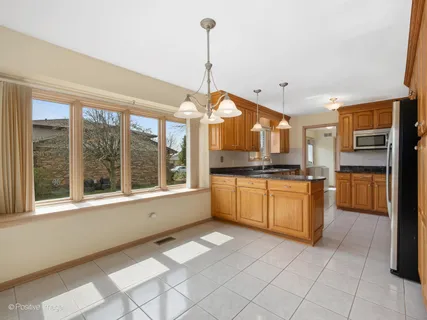 a kitchen with stainless steel appliances granite countertop a refrigerator a sink and white cabinets