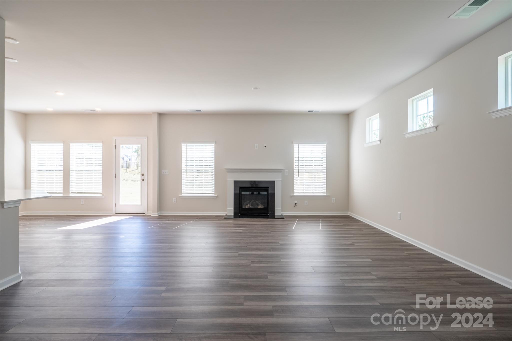 15307 Lake Ridge Road Charlotte, NC 28278 - Photo 11 of 33 an empty room with wooden floor fireplace and windows