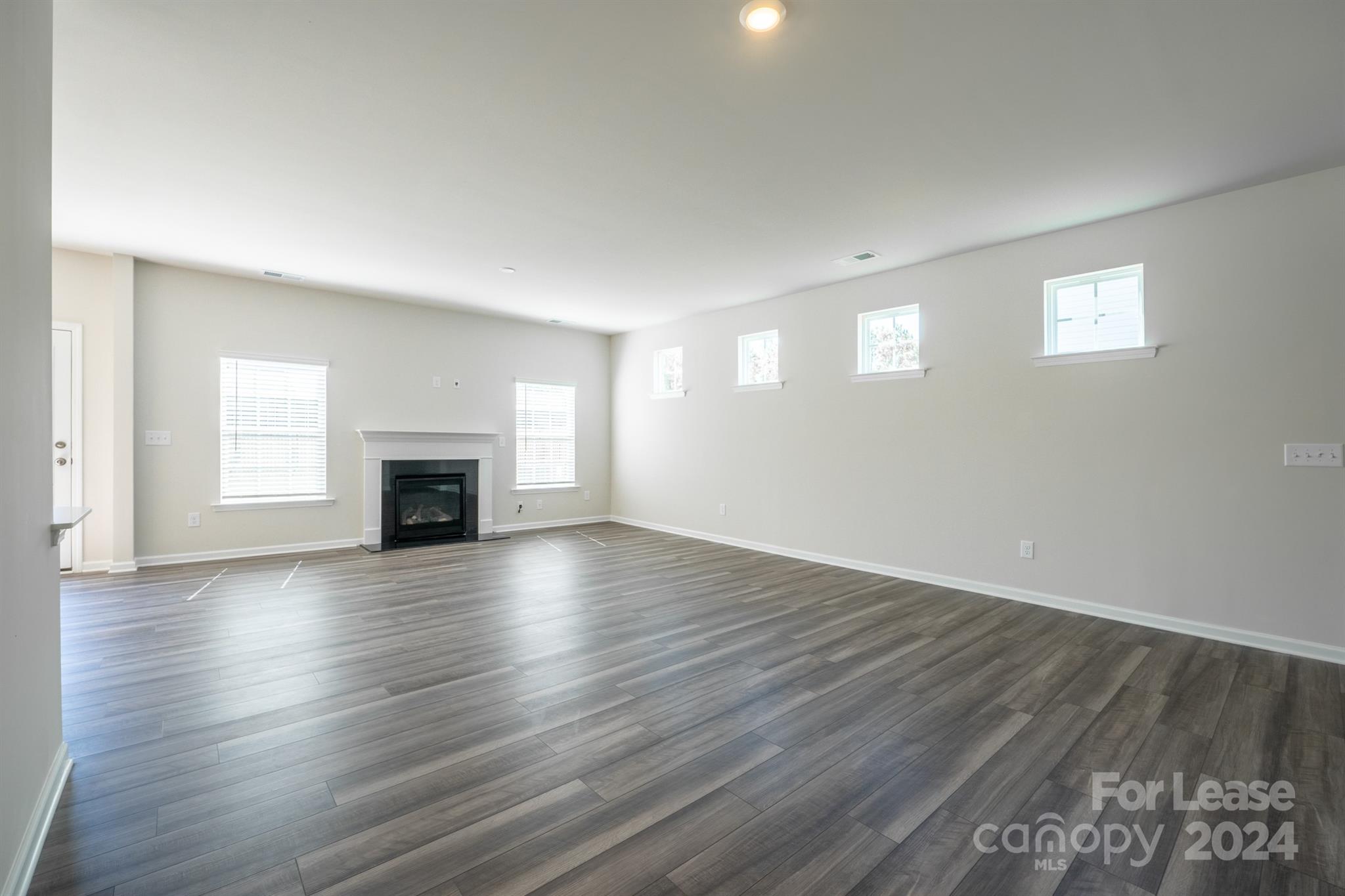 15307 Lake Ridge Road Charlotte, NC 28278 - Photo 3 of 33 an empty room with wooden floor fireplace and windows