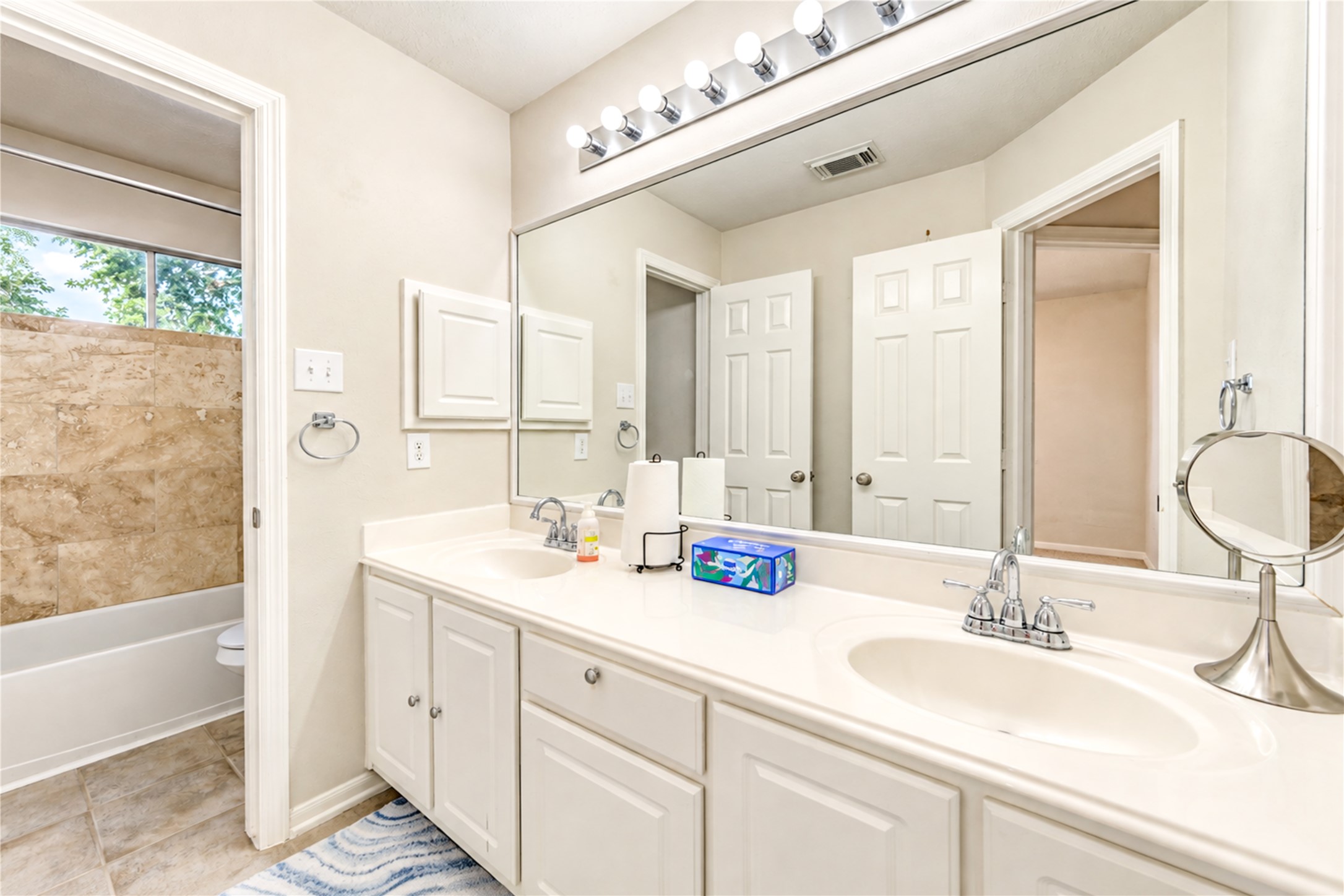 12806 Ridge Bank Lane Houston, TX 77041 - Photo 30 of 44 Bright and spacious secondary bathroom featuring a double sink vanity with ample storage, large mirror, and elegant tile accents in the bathtub area.