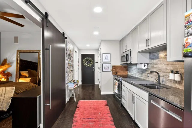 a open kitchen with stainless steel appliances granite countertop a refrigerator a stove and a wooden cabinets