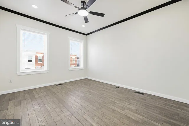 an empty room with wooden floor fan and windows