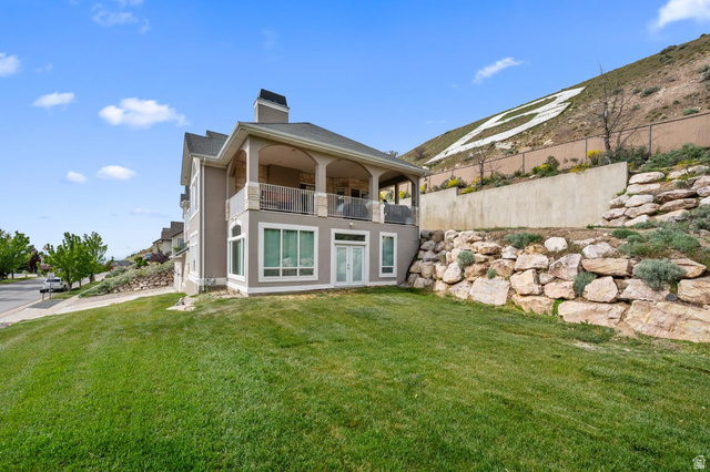 708 Eagle Rdg Drive Bountiful, UT 84010 - Photo 69 of 69 Contemporary architecture featuring a stucco exterior, a second-story covered balcony with stone accents, and expansive ground-level windows