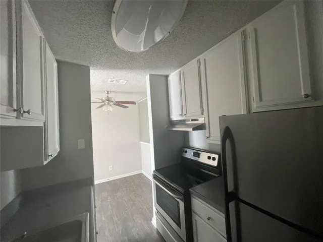 an empty room with wooden floor chandelier and windows
