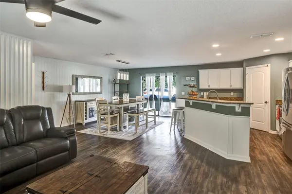 a living room with stainless steel appliances furniture and wooden floor