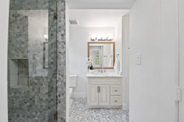 a bedroom with a bed and a lamp on dresser