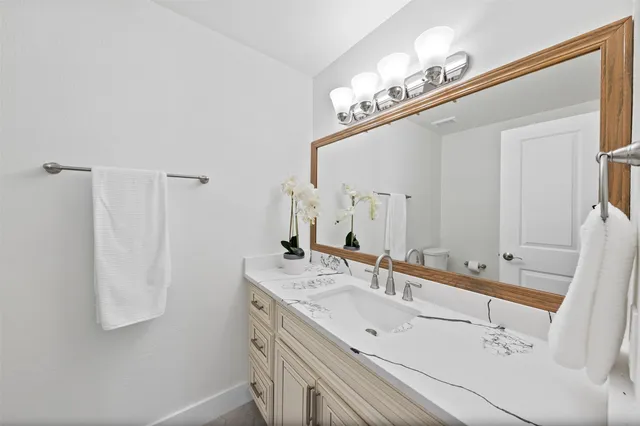 a bathroom with a granite countertop sink a toilet and shower