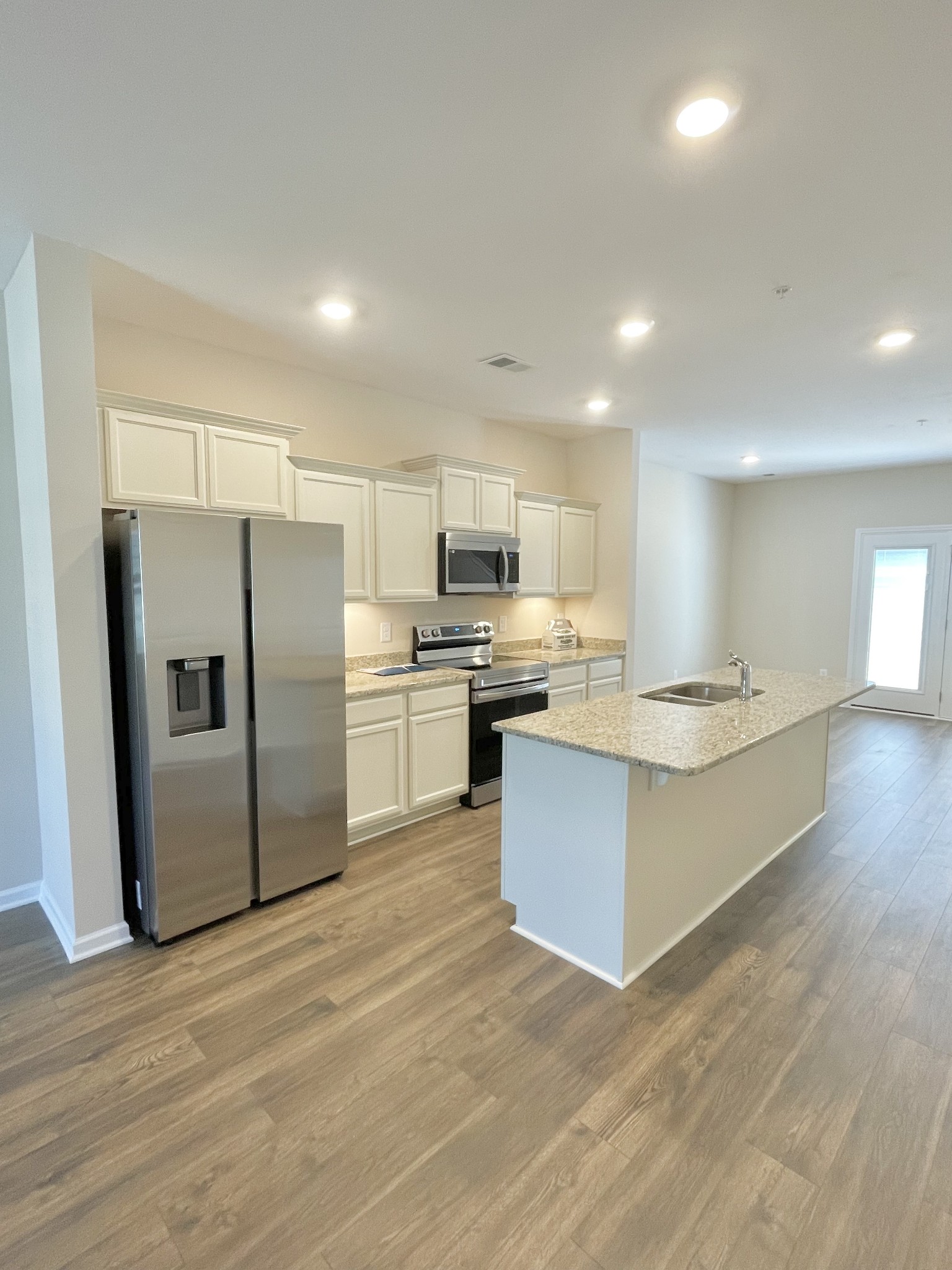 125 Addi Street Pleasant View, TN 37146 - Photo 5 of 14 a large kitchen with stainless steel appliances a large counter top a stove a sink dishwasher a refrigerator and white cabinets with wooden floor