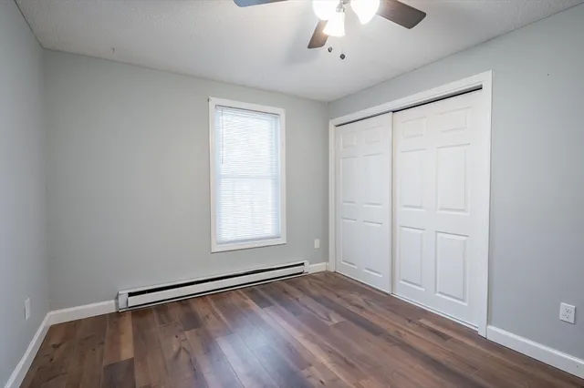 an empty room with wooden floor chandelier fan and windows