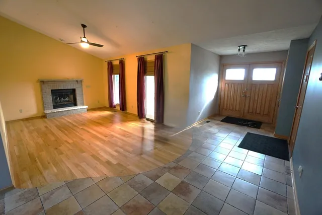 a view of an empty room with window and chandelier fan