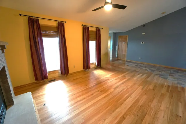 a view of an empty room with window and wooden floor