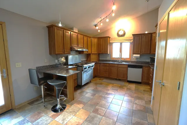 a kitchen with kitchen island granite countertop a sink cabinets and stainless steel appliances