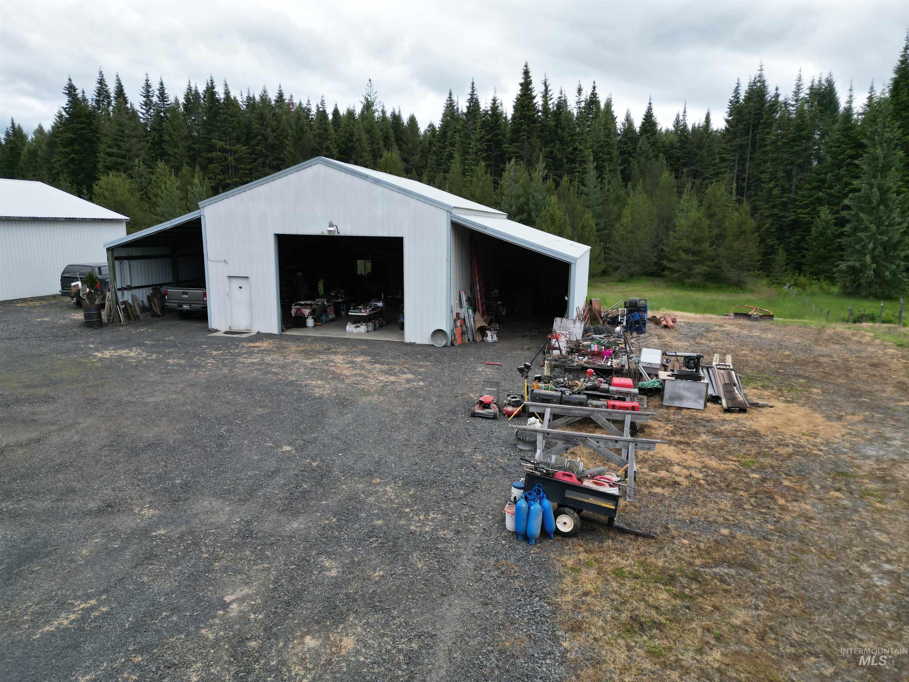 254 Lackey Road Weippe, ID 83553 - Photo 19 of 38 White metal utility building featuring a covered side extension, overhead garage door access, and a secondary personnel door