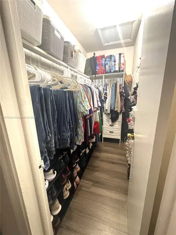 a view of walk in closet with clothes and shoes