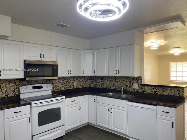 a kitchen with granite countertop white cabinets and white appliances