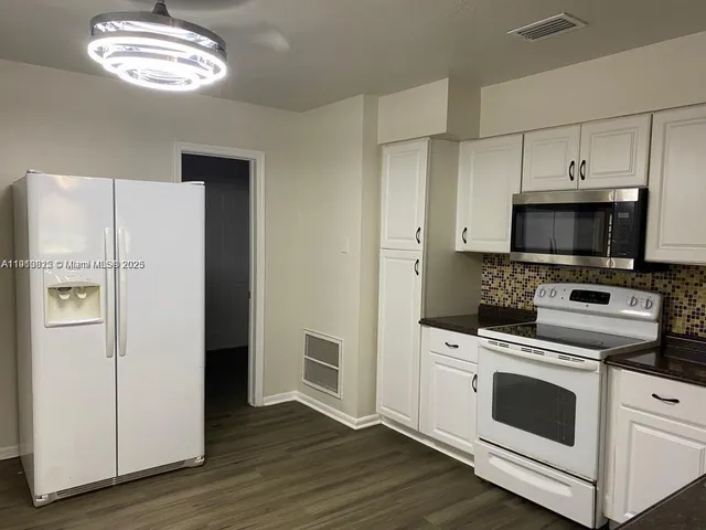 a kitchen with stainless steel appliances white cabinets and a refrigerator