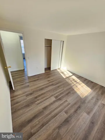a view of an empty room with wooden floor and stairs
