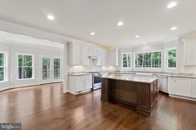 a kitchen with kitchen island granite countertop a stove cabinets and wooden floor