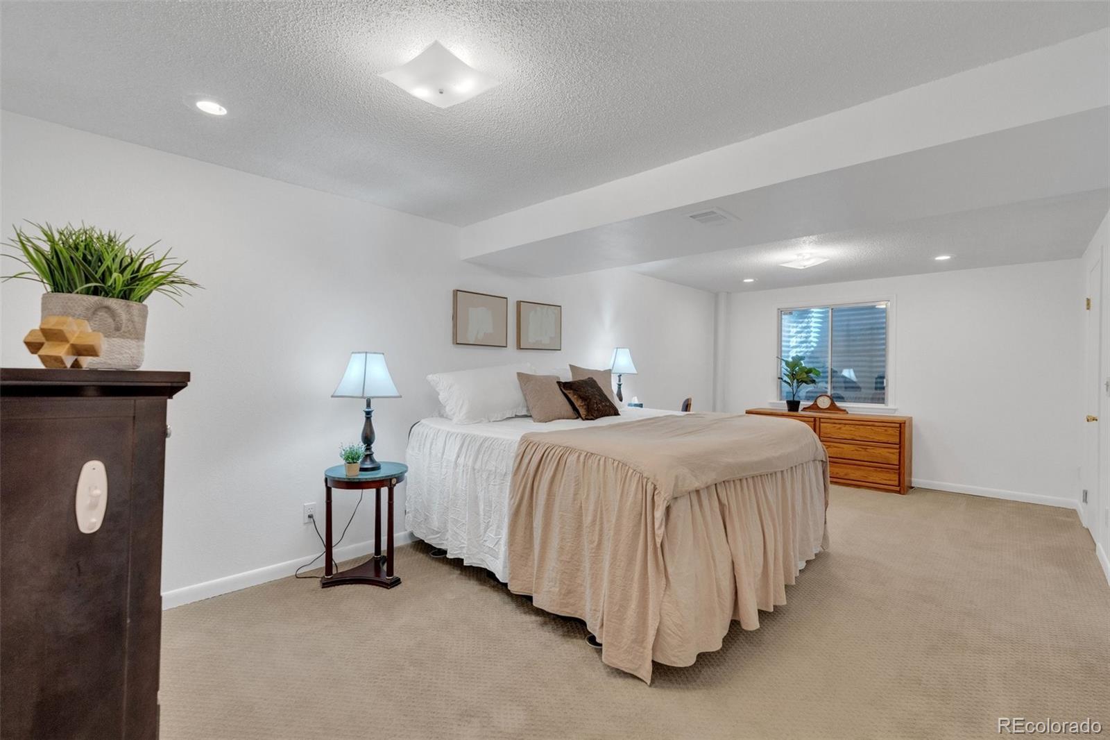 4320 Genoa Street Denver, CO 80249 - Photo 15 of 48 a spacious bedroom with a bed and a lamp