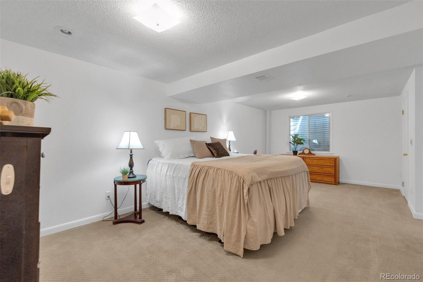 4320 Genoa Street Denver, CO 80249 - Photo 16 of 48 a spacious bedroom with a bed and a lamp