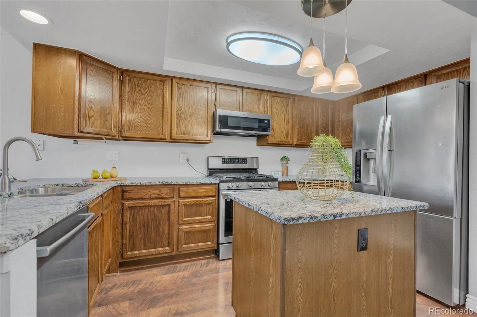 4320 Genoa Street Denver, CO 80249 - Photo 33 of 48 a kitchen with stainless steel appliances granite countertop a sink refrigerator stove and microwave