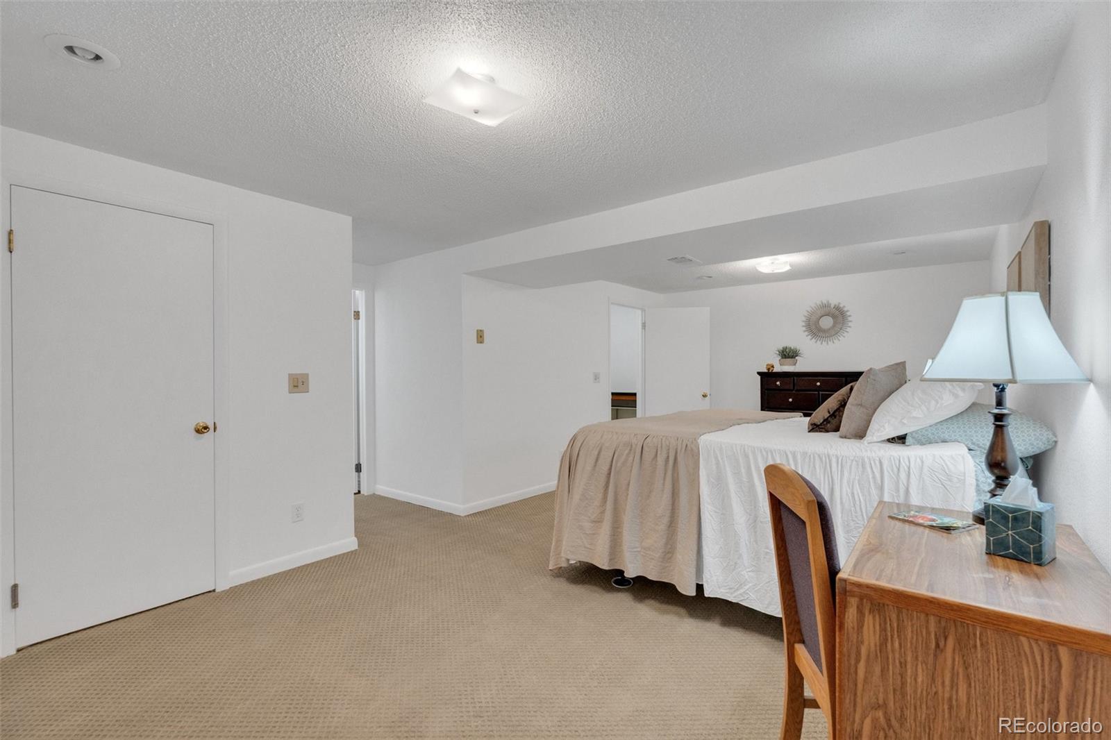 4320 Genoa Street Denver, CO 80249 - Photo 35 of 48 a spacious bedroom with a bed and a lamp