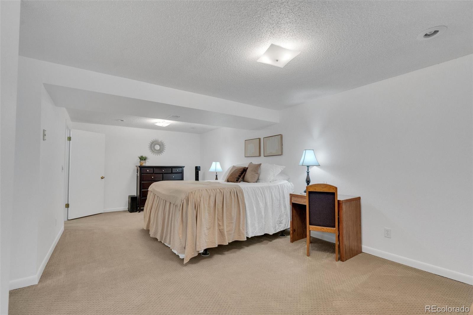 4320 Genoa Street Denver, CO 80249 - Photo 44 of 48 a spacious bedroom with a bed and a lamp
