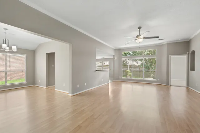 a view of an empty room with wooden floor and a window