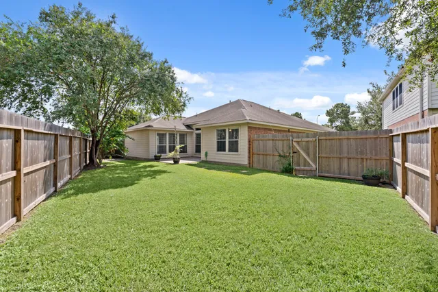 a view of a house with backyard and wooden fence