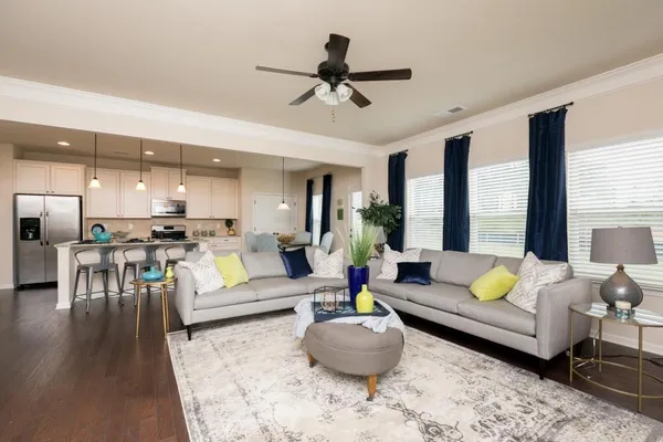 a living room with furniture kitchen view and a large window