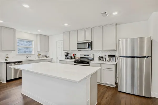 a kitchen with a table chairs a wooden floor and a large window