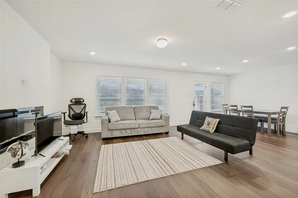a living room with a couch and kitchen view with wooden floor