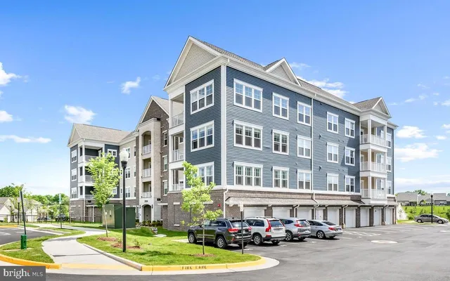 a front view of a building with lot of cars and trees