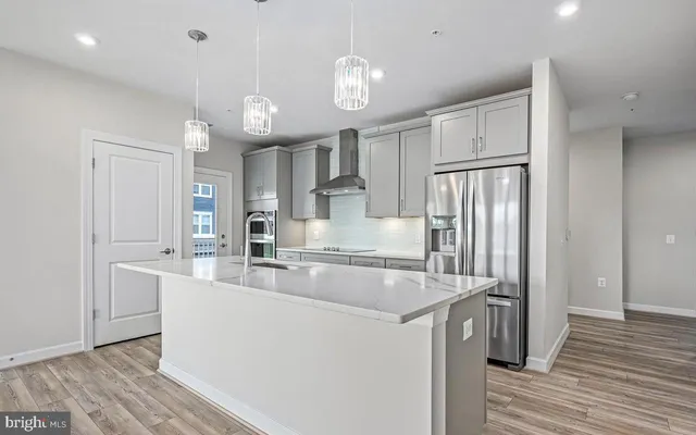 a large kitchen with stainless steel appliances a large counter top a sink cabinets and a wooden floor